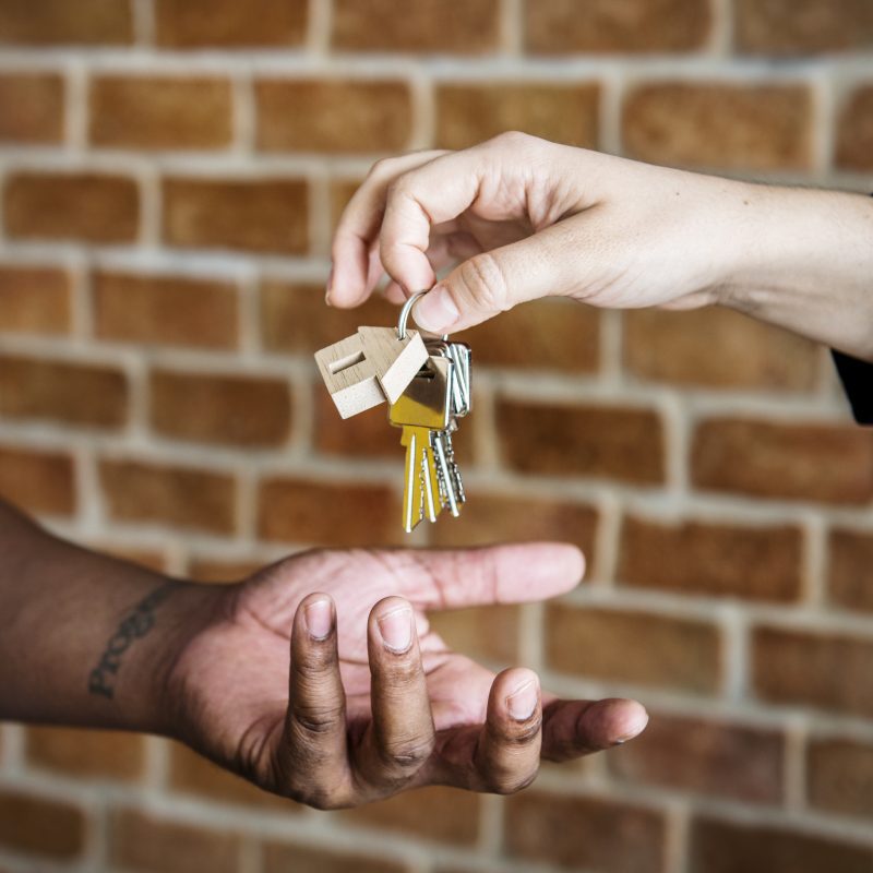 passing keys in front of brick wall illustrating when you sell your house directly to investors